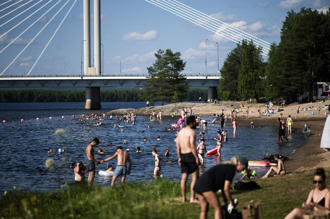 Des personnes se baignant sur la plage d’Ounaskoski, au cercle polaire arctique, à Rovaniemi, en Laponie finlandaise, le 23 juillet 2025.