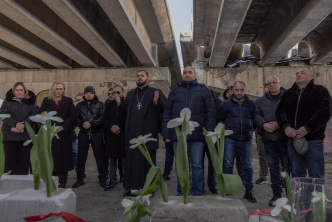 Des personnes assistent à une cérémonie commémorative sous un pont détruit à Irpin, au nord-ouest de Kiev, le 24 février 2025, à l’occasion du troisième anniversaire de l’invasion de l’Ukraine par la Russie.