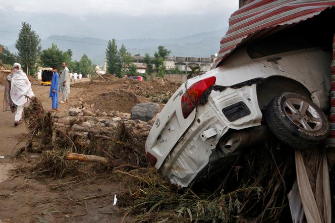 Une femme passe devant un véhicule endommagé à la suite de fortes pluies et d’inondations dans le district de Buner, dans la province de Khyber Pakhtunkhwa, au Pakistan, le 16 août 2025.
