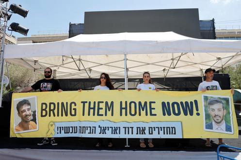 Yarden Bibas, Sharon Cunio en Arbel Yehud, voormalige Israëlische gijzelaars die zijn bevrijd uit Hamas-gevangenschap, en Eitan Cunio, wiens broer David nog steeds in Gaza zit, houden een spandoek vast tijdens een protest op het Gijzelaarsplein in Tel Aviv op 17 augustus 2025.