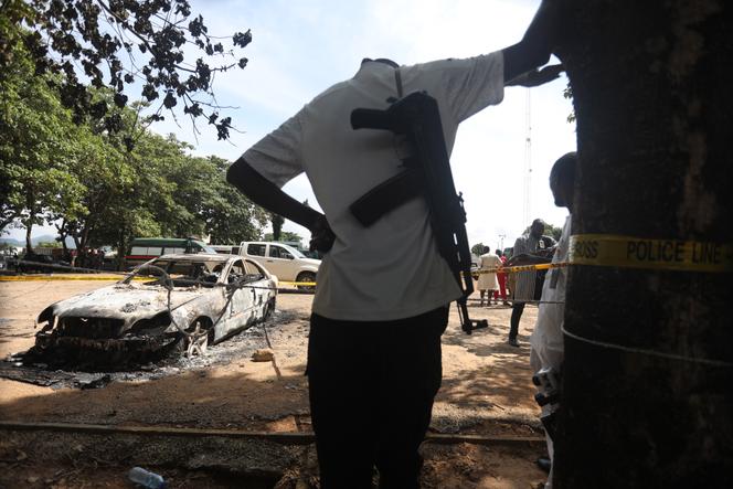 Un policier se tient près d’un véhicule brûlé lors de l’attaque de la prison de Kuje, au Nigeria, le 6 juillet 2022.