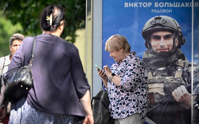 A un arrêt de bus, à côté d’une affiche représentant un soldat de l’armée russe, dans le centre de Moscou, le 5 août 2024.