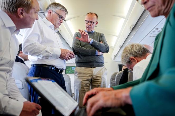 Le chancelier allemand Friedrich Merz (au centre) s’entretient avec des journalistes à bord de l’Airbus A319 de l’armée de l’air à destination de Washington, le 18 août 2025.