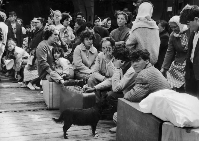 Rapatriés d’Algérie arrivés à Marseille, attendant sur le pont d’un bateau, en 1962.