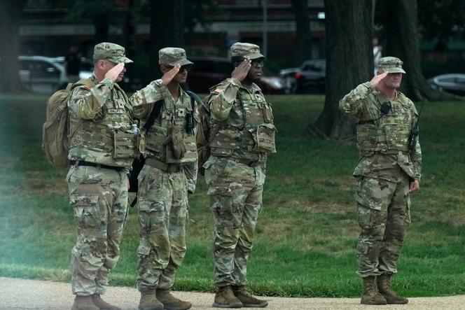 Des soldats de la garde nationale font un salut militaire au passage du convoi présidentiel, près de la Maison blanche, à Washington, jeudi 21 août 2025.