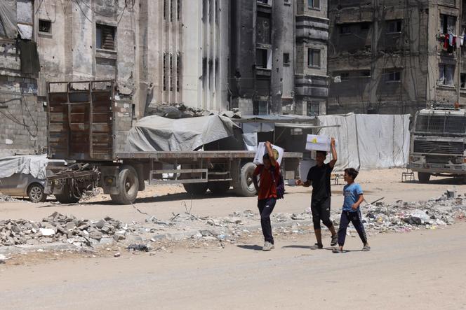 Des Palestiniens transportent de l’aide humanitaire, qu’ils ont récupérée après un largage, près de Jabalia, dans le nord de la bande de Gaza, le 20 août 2025.