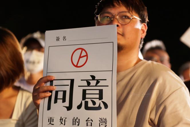 Un homme tient une pancarte sur laquelle est inscrit « Approbation » pour soutenir le référendum organisé quant à la prolongation de l’exploitation de la troisième centrale nucléaire à Taipei, à Taïwan, le vendredi 22 août 2025.