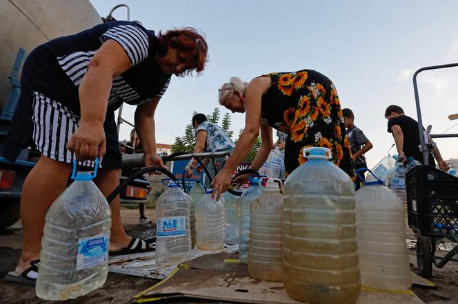 Des habitants remplissent des bouteilles avec de l’eau livrée par camion-citerne, à Donetsk, dans l’est de l’Ukraine, le 21 août 2025.