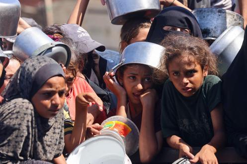 Mulheres e crianças esperam para receber comida de uma cozinha beneficente em Khan Younis, sul da Faixa de Gaza, 27 de agosto de 2025.