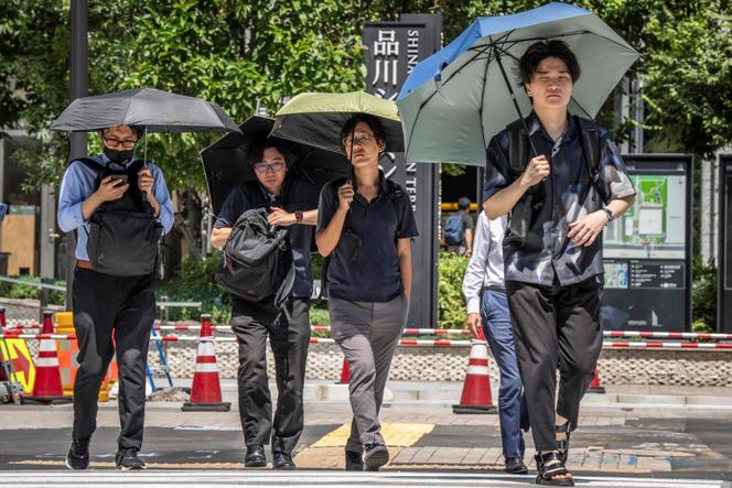 Des passants se protègent du soleil sous des ombrelles, à Tokyo, le 27 août 2025.