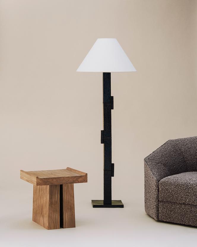 Le bout de canapé en chêne Rocky, le lampadaire Domino et le fauteuil Otto, d’Adret.