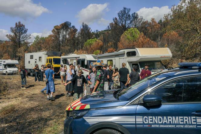 Des fêtards attendent à côté de leurs véhicules pour accéder au site d’une rave-party organisée au milieu d’un terrain calciné à Fontjoncouse, dans le département français de l’Aude, le 30 août 2025.