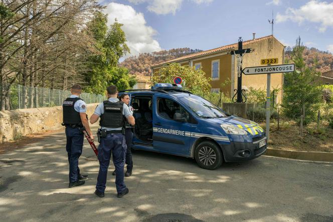 Des gendarmes se tiennent à côté de leur véhicule alors qu’ils contrôlent l’accès à une rave organisée au milieu d’un terrain calciné à Fontjoncouse, dans le département français de l’Aude, le 30 août 2025.