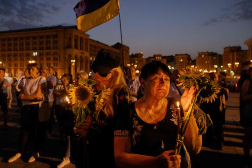 Une femme tient une bougie et un tournesol lors d’une cérémonie en hommage à l’ancien président du Parlement ukrainien Andri Paruobi, à Kiev, le 1ᵉʳ septembre 2025.