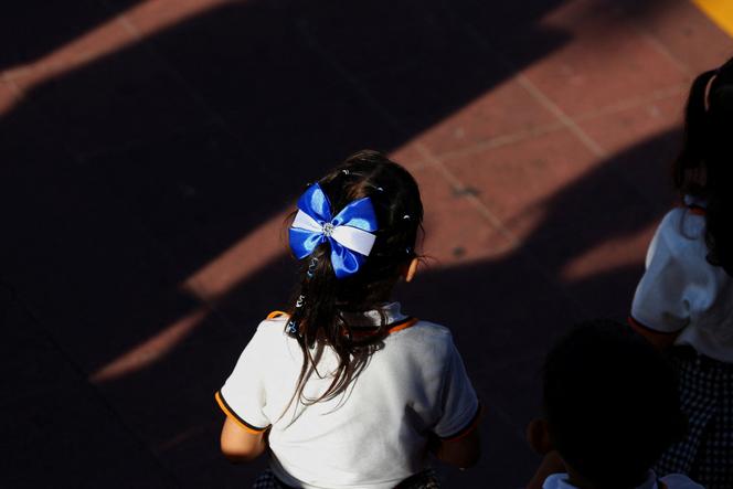 Une élève porte un nœud aux couleurs du drapeau salvadorien lors d’une cérémonie marquant le début du mois de l’indépendance, à San Salvador, le 1er septembre 2025.