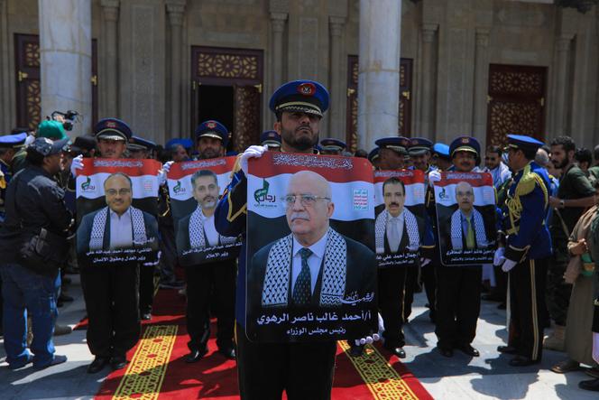 La garde d’honneur yéménite brandit les portraits du premier ministre du gouvernement yéménite dirigé par les houthistes, Ahmed Ghaleb Al-Rahwi, et d’autres responsables, tués durant une frappe israélienne quelques jours plus tôt, lors d’un cortège funèbre à Sanaa, le 1er septembre 2025.