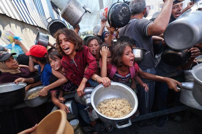 Des Palestiniens se bousculent pour recevoir un repas chaud distribué par une cuisine caritative dans le camp de réfugiés de Nuseirat, dans la bande de Gaza assiégée par Israël, le 4 septembre 2025.