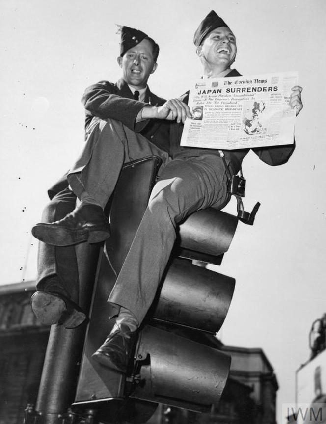 Le sergent Franklin G. Talley et un membre de la Royal Air Force (RAF) brandissent le journal « Evening News » dont la une proclame « Japan Surrenders » (« le Japon se rend »), à Londres, en août 1945.