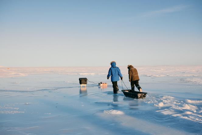 Des bénévoles récupèrent une pompe d’eau de mer sur la banquise, à Cambridge Bay, au Nunavut (Canada), en février 2025. Ce projet de recherche vise à pomper l’eau de mer et à la diffuser à la surface, afin qu’elle gèle.