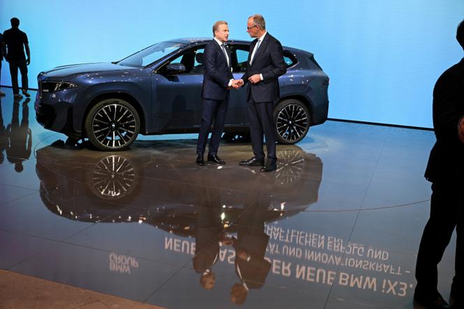 Le chancelier allemand, Friedrich Merz (à droite), et le PDG de BMW, Oliver Zipse, devant une BMW iX3, au salon international de l’automobile de Munich (Bavière), le 9 septembre 2025.