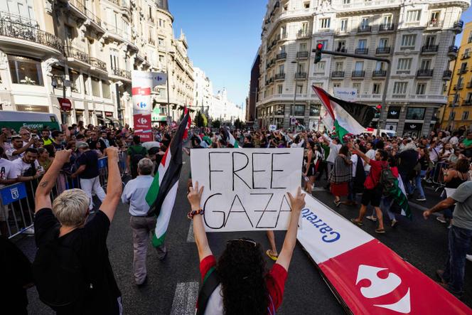 Des manifestants propalestiniens brandissent une banderole et des drapeaux palestiniens après avoir envahi la rue et forcé les organisateurs de la course à abandonner la 21ᵉ et dernière étape de la Vuelta 2025, à Madrid, le 14 septembre 2025.