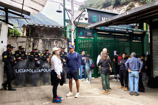 Des policiers montent la garde à côté d’un groupe de touristes à la gare ferroviaire de Machu Picchu Pueblo, au Pérou, le 16 septembre 2025.  