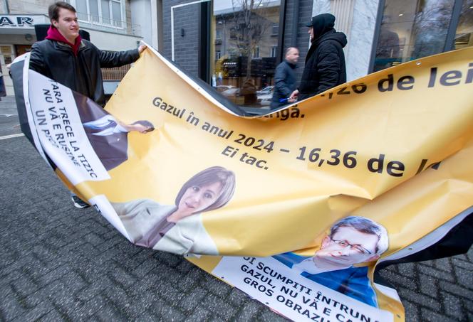 Une manifestation devant le siège de l’Agence nationale de régulation de l’énergie contre l’augmentation du prix du gaz. Sur la banderole figure les photos du ministre des affaires étrangères, Mihai Popsoi, de la présidente de Moldavie, Maia Sandu, et du président du Parlement, Igor Grosu, à Chisinau, le 29 novembre 2024.