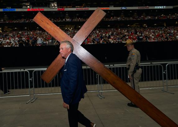A man carries a cross during the memorial for Charlie Kirk at State Farm Stadium in Glendale, Arizona, on September 21, 2025.