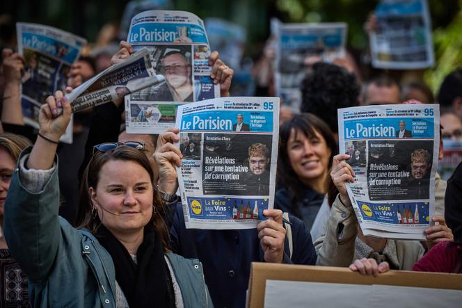 Des journalistes et des membres du personnel du quotidien « Le Parisien » brandissent des exemplaires de leur journal alors qu’ils se rassemblent devant le siège du groupe Les Echos-Le Parisien pour protester contre la rumeur de vente du journal au groupe Bolloré, à Paris, le 22 septembre 2025.