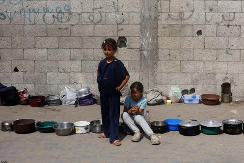 Des enfants attendent de recevoir de la nourriture d’une cuisine caritative, à Nousseirat, dans le centre de la bande de Gaza, le 28 septembre 2025.