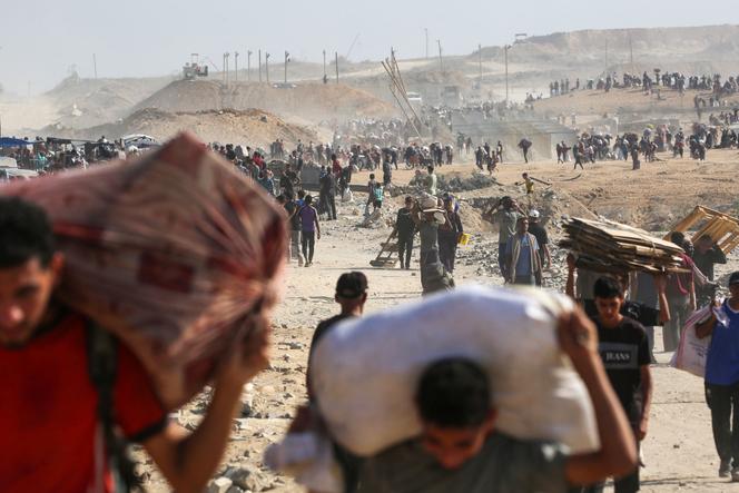 Des Palestiniens avec des sacs d’aide humanitaire reçus dans un centre de distribution de la Gaza Humanitarian Foundation, soutenue par les Etats-Unis et Israël, dans le corridor de Netzarim, à Nousseirat, dans la bande de Gaza, le 26 septembre 2025.