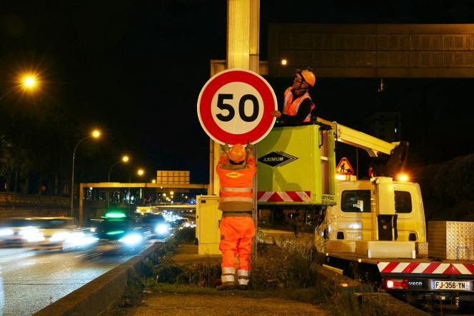 Des ouvriers installent un panneau de limitation de vitesse à 50 km/h sur le boulevard périphérique, à hauteur de la porte d’Ivry, le 30 septembre 2024. 