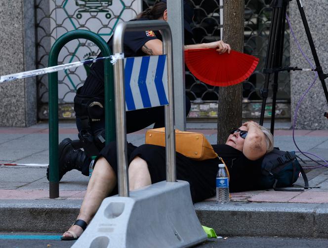 Une policière espagnole ventile une femme allongée sur le trottoir après avoir fait un malaise, lors d’une vague de chaleur à Madrid, où la température a atteint les 40°, le 5 juillet 2025.