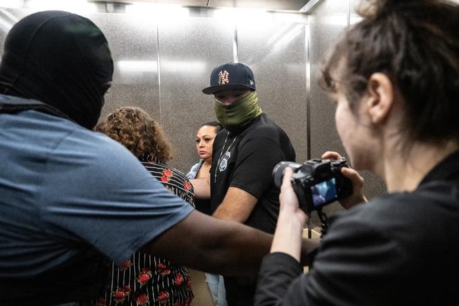 Des agents de la police de l’immigration américaine (ICE) font sortir Dean Moses, photographe du journal « AM New York », de l’ascenseur d’un tribunal situé dans le Jacob K. Javits Federal Building, alors qu’ils arrêtent un migrant, à New York, le 30 septembre 2025.