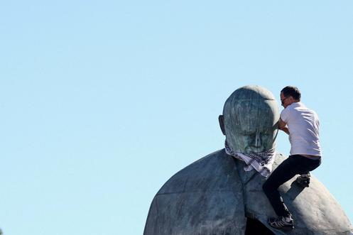 Un manifestant propalestinien escalade une statue de Jean Paul II pour y installer un keffieh, à Rome, le 3 octobre 2025.