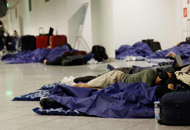 Des passagers dorment sur des matelas gonflables à l’aéroport de Munich (Allemagne), le 4 octobre 2025.