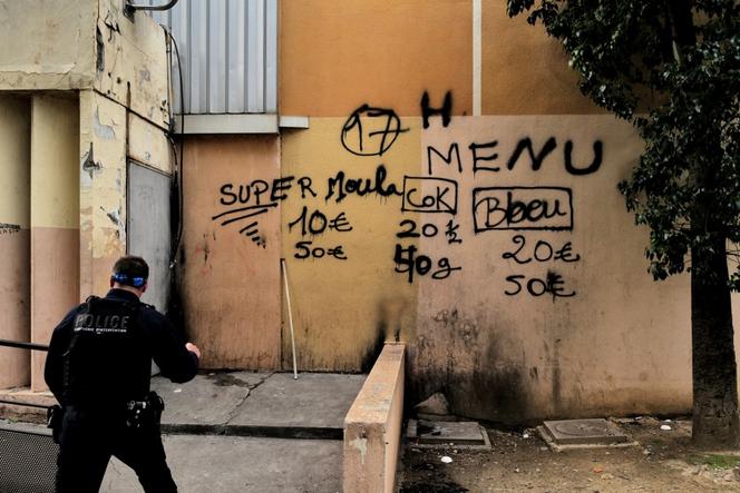 Un policier devant un mur indiquant les prix des drogues, lors d’une opération de police dans le quartier des Moulins, à Nice, en janvier 2023.