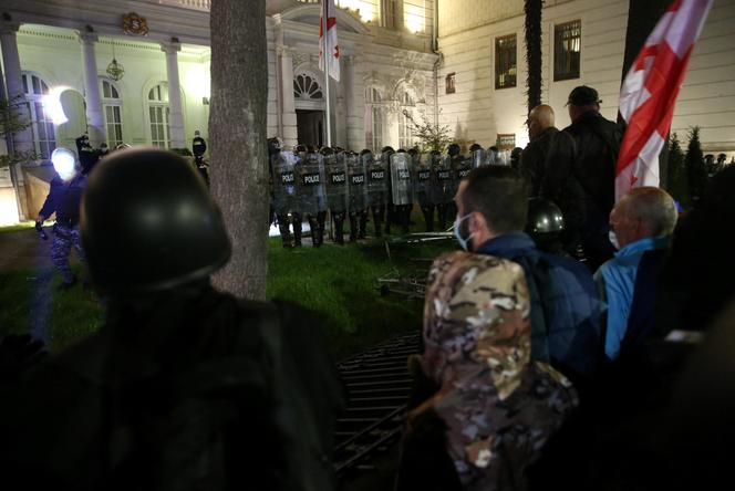 Des policiers géorgiens face à des manifestants qui tentent de pénétrer dans l’enceinte du palais présidentiel, à Tbilissi, en Géorgie, le 4 octobre 2025. 