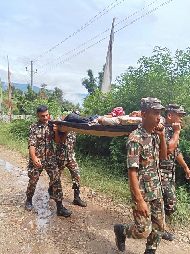 Des soldats népalais portent un homme ayant survécu à un glissement de terrain dans la région d’Ilam, dimanche 5 octobre 2025.