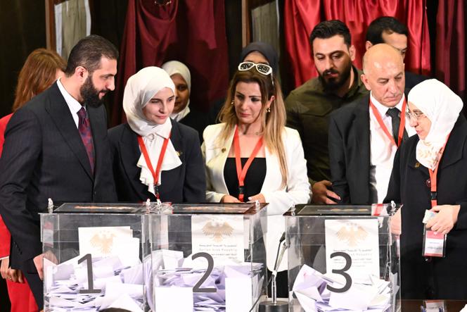 A gauche, le président intérimaire Ahmed Al-Charaa, dans un bureau de vote où les membres des comités locaux votent pour la désignation du futur Parlement, à Damas, le 5 octobre 2025.