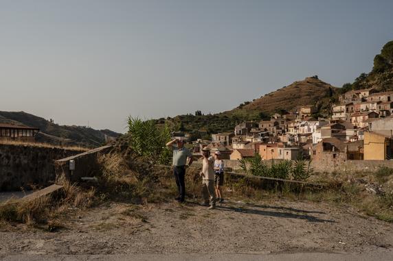 Le maire de Saponara, Giuseppe Merlino, observe avec deux habitants, Manu Reggi et Donatella Ruggeri, les lieux touchés par des coulées de boue dans le village, le 26 août 2025.