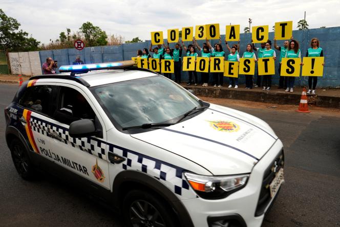 Un véhicule de la police militaire brésilienne passe devant un rassemblement d’activistes de Greenpeace, sur la route menant à Belem, où se tiendra la COP30, à Brasilia, le 13 octobre 2025.