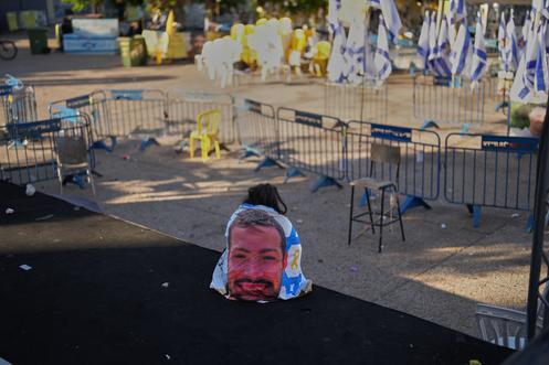 Женщина, завернутая во флаг с портретом сержанта Итая Чена, служившего в 77-м батальоне 7-й бригады, на «Площади заложников» в Тель-Авиве, 14 октября 2025 года.