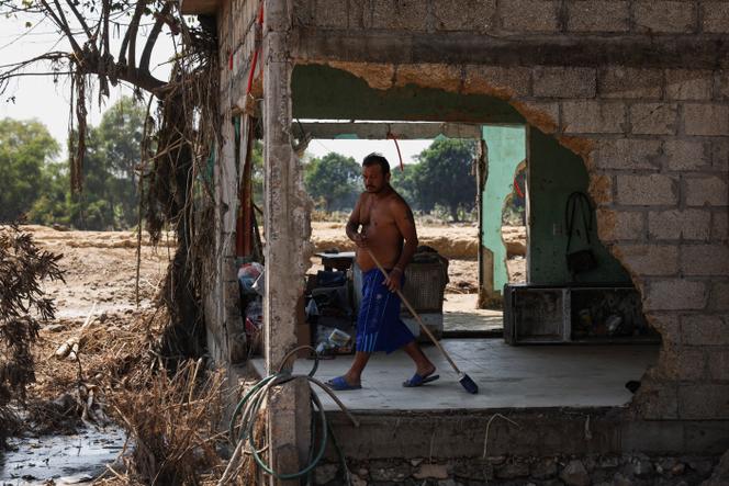 Un homme nettoie le sol d'une maison endommagée par des inondations, après des pluis torrentielles, à Poza Rica, au Mexique, le 16 octobre 2025.