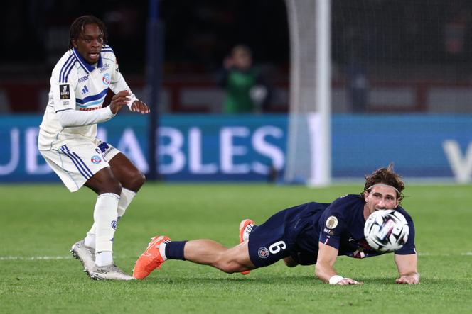 Le défeNseur du Paris Saint-Germain Illia Zabarnyi, au sol après un duel avec l’attaquant strasbourgeois Martial Gogo, au Parc des Princes, à Paris, le 17&nbsp;octobre&nbsp;2025.