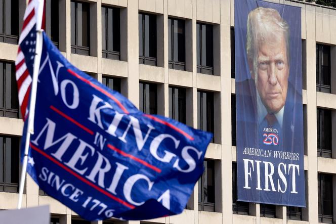 Devant une banière monumentale à l’effigie de Donald Trump, flotte un drapeau « Pas de rois en Amérique » lors d’une manifestation contre la politique du président des Etats-Unis, à Washington, le 18 octobre 2025. 