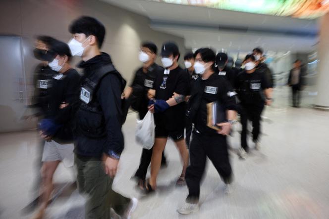 Des officiers de police escortent des Sud-Coréens accusés de prendre part à des opérations d’arnaques sur Internet, à leur arrivée à l’aéroport international d’Incheon (Corée du Sud), le 18 octobre 2025.