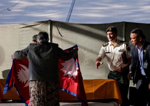 La première ministre du Népal, Sushila Karki, couvre le cercueil de l’otage Bipin Joshi du drapeau du pays, après que son corps a été ramené au Népal, à l’aéroport international Tribhuvan de Katmandou, le 20 octobre 2025.