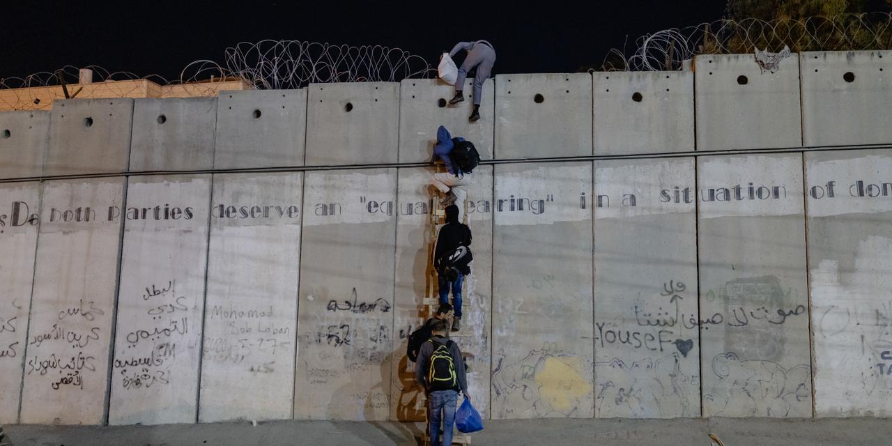 LAURENCE GEAI/MYOP POUR « LE MONDE » Près de Ramallah, le 11 octobre 2025. Des hommes escaladent le mur de séparation à l'aide d'une échelle. Ils partent travailler en Israel. Depuis le 7octobre 2023, de nombreux permis de travail ont été supprimés. Depuis cette date, 55 personnes auraient été abattues par l'armée israélienne en essayant de traverser illégalement. Le mur mesure entre 8 et 10m.