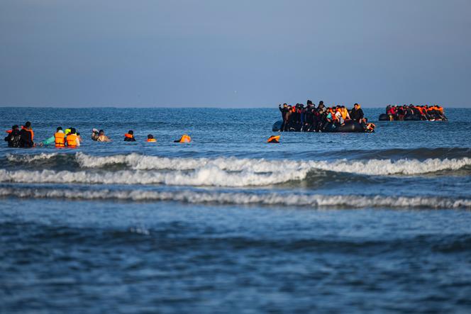 Des migrants s’avancent dans la mer pour tenter de monter à bord de bateaux afin de traverser la Manche, au large de la plage de Gravelines, dans le nord de la France, le 27 septembre 2025.